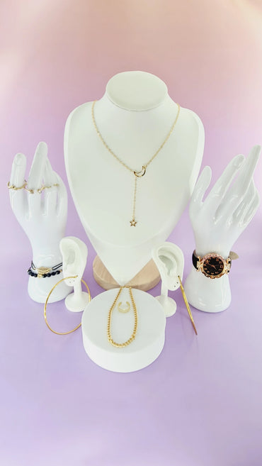 Présentation bijoux femme 974 reunion : collier lune, montre dorée, bagues, bracelets sur fond violet.
