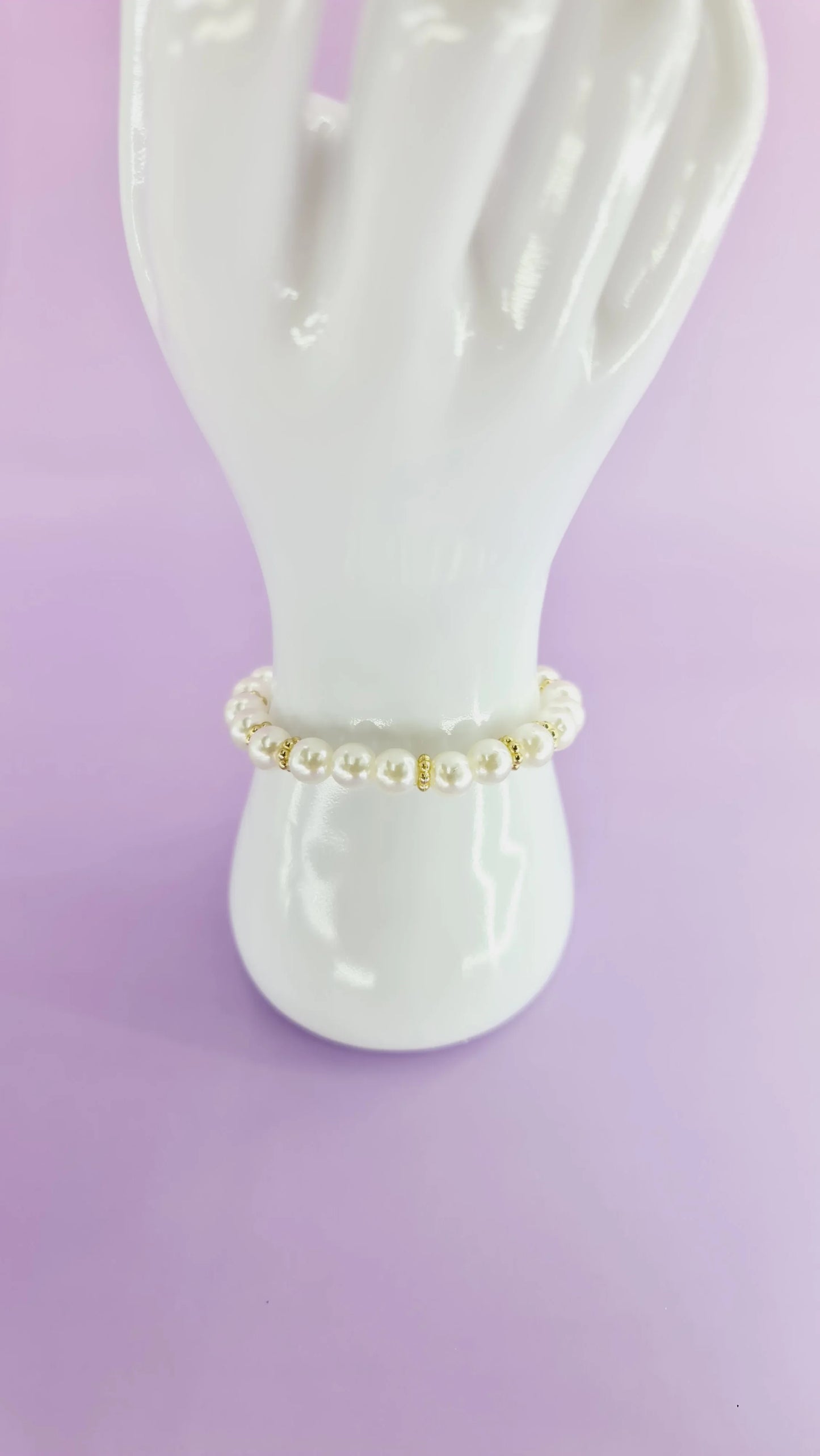 Bracelet perles blanches et dorées sur support, bijou tendance 974 Réunion, fond violet.