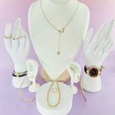 Présentation bijoux femme 974 reunion : collier lune, montre dorée, bagues, bracelets sur fond violet.