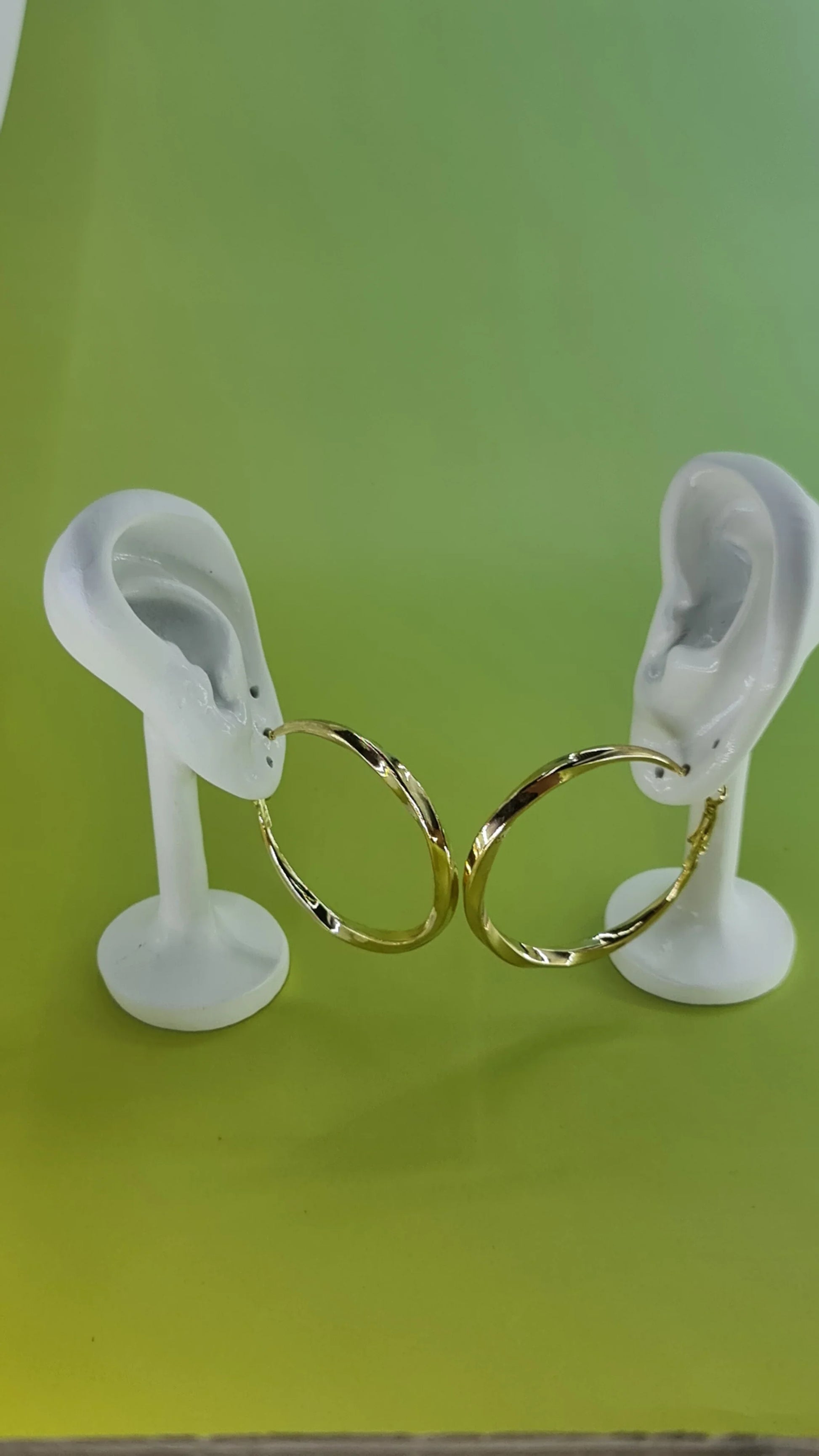 Boucles d'oreilles créoles dorées sur support oreilles, fond vert, 974 Réunion