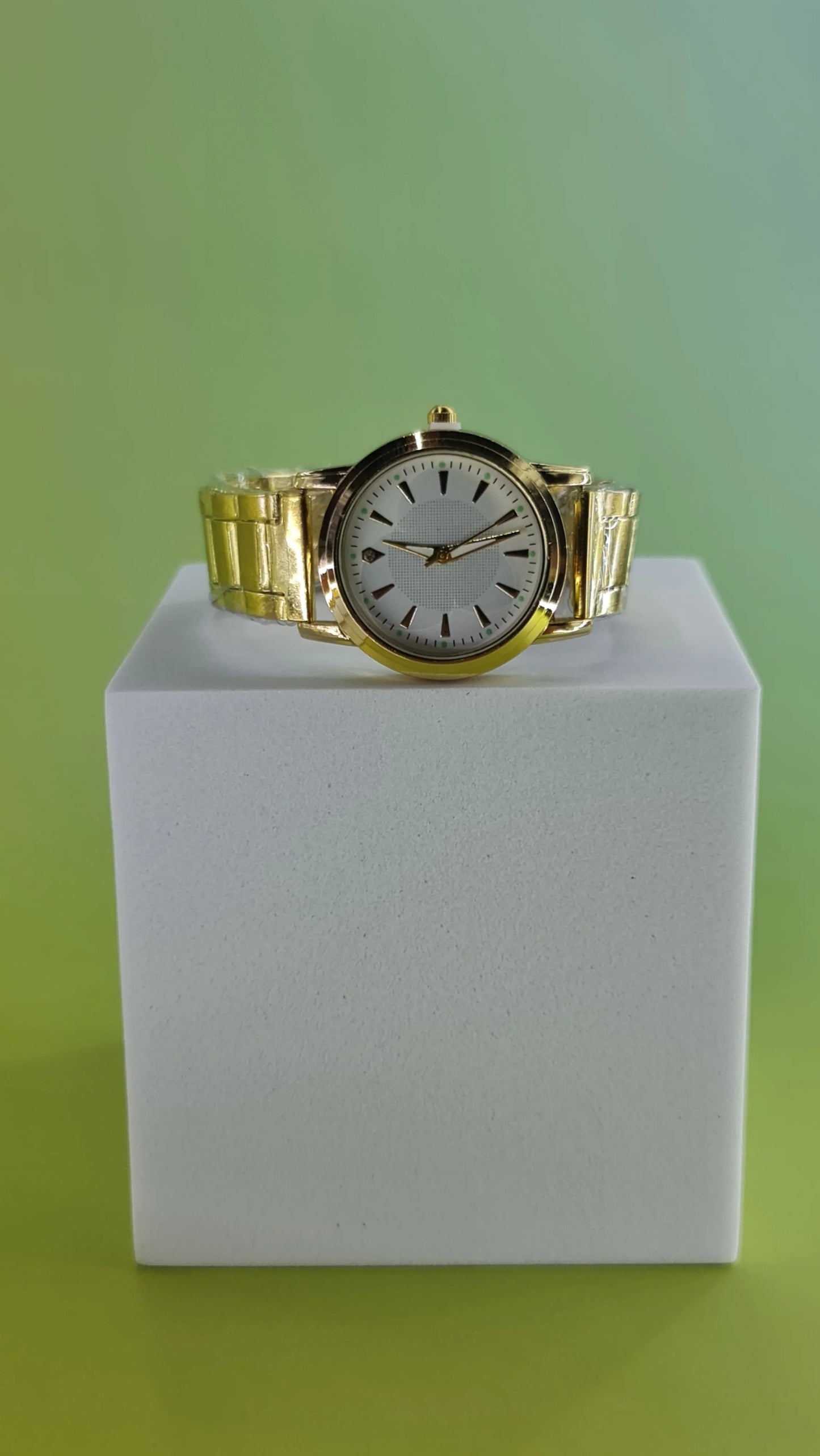 montre dorée femme affichée sur socle, fond vert, accessoire mode 974 Réunion