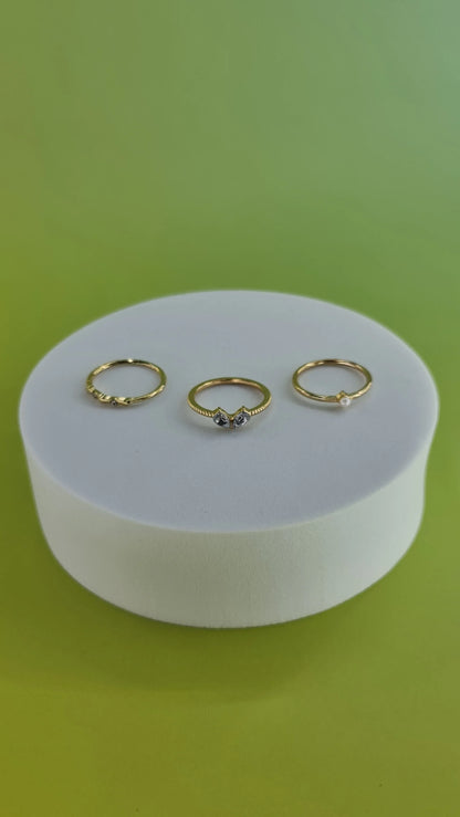 Trois bagues fines dorées sur support blanc, fond vert, bijoux femme 974 Réunion