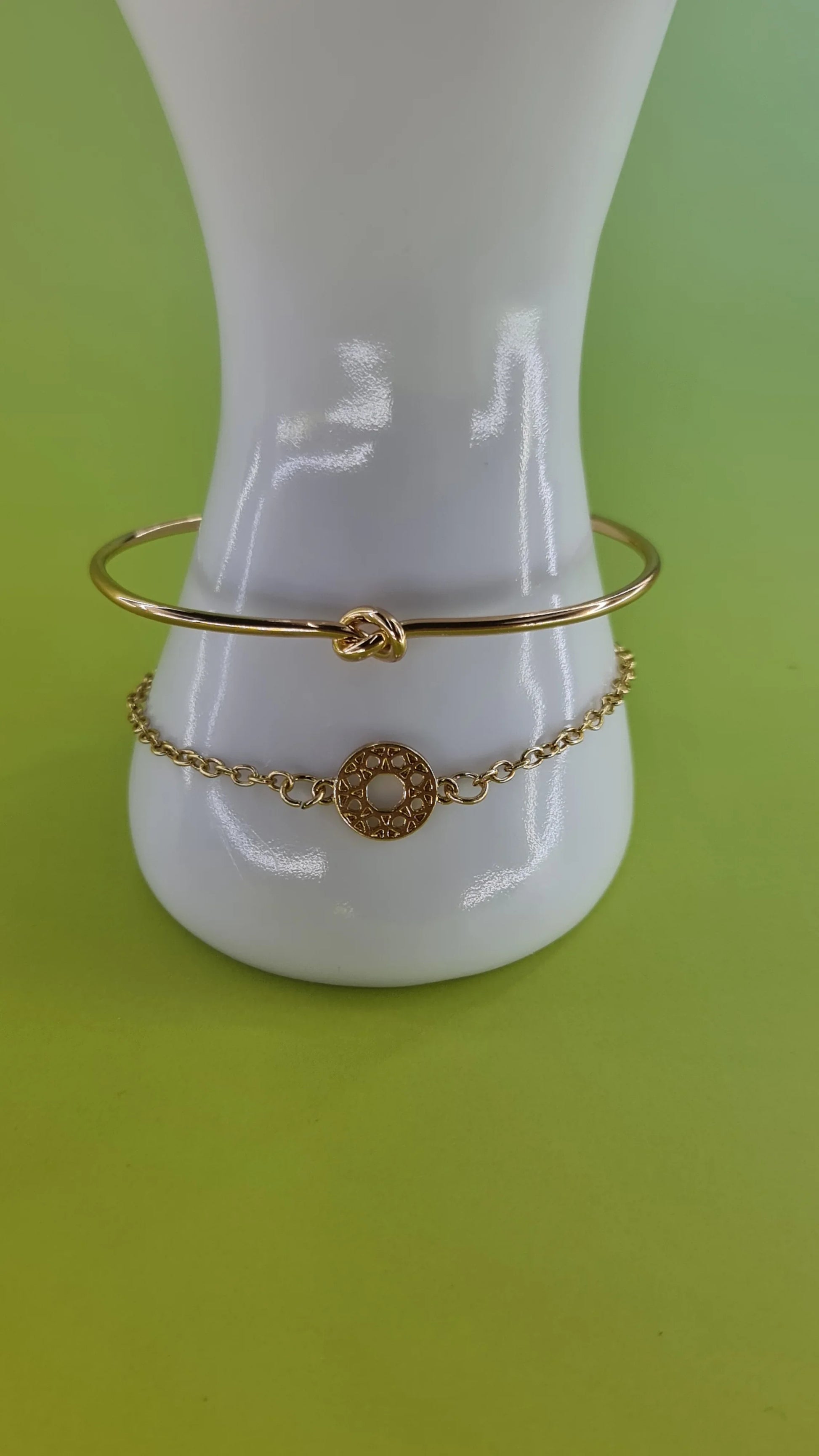 Duo de bracelets dorés femme, motif cercle et noeud, bijou tendance 974 Réunion, fond vert.