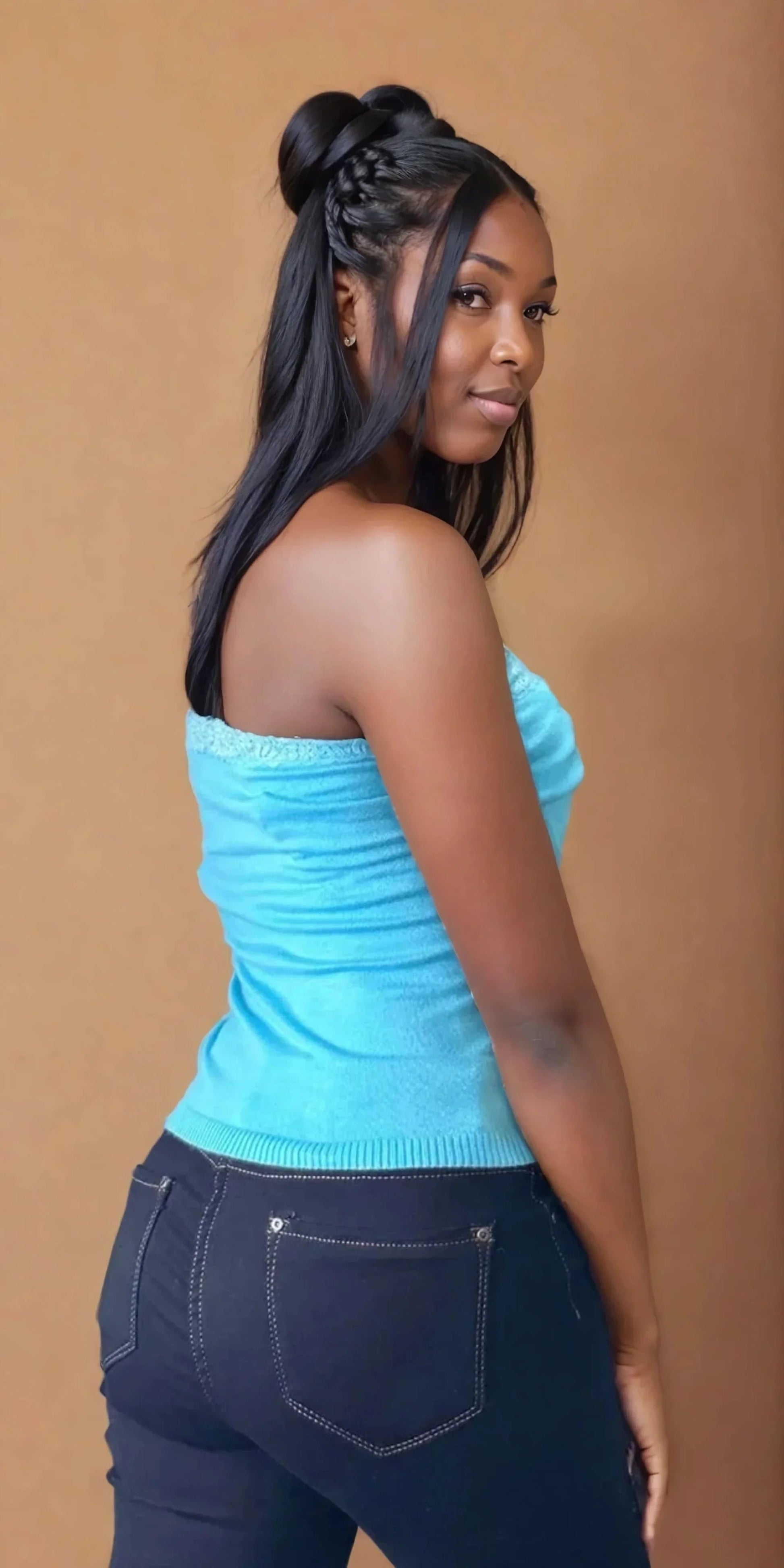 Femme portant un bustier turquoise et un jean, mode tendance 974 Réunion, fond neutre.