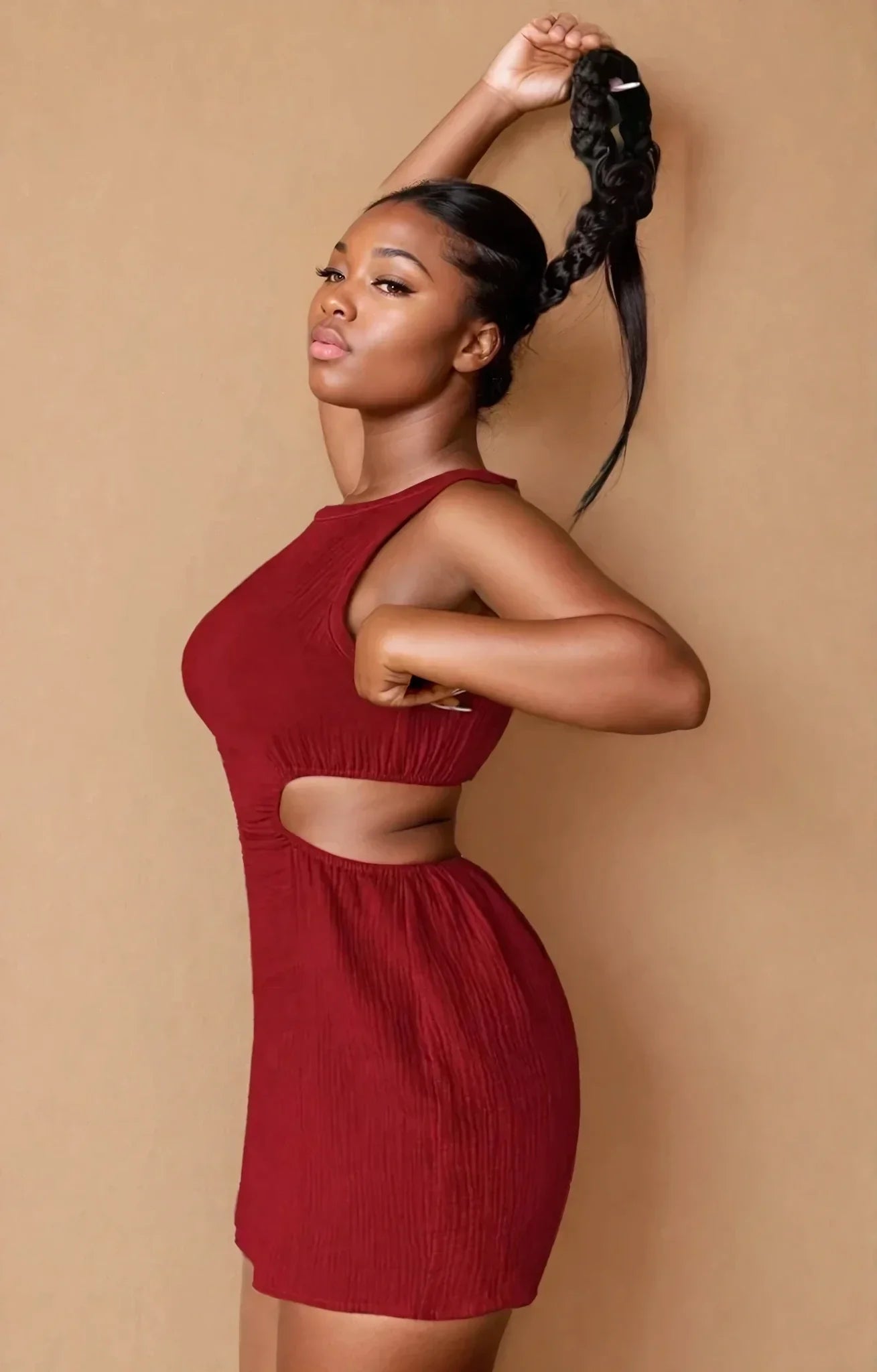 Femme portant une robe bordeaux échancrée tendance, mode 974 Réunion, fond beige.