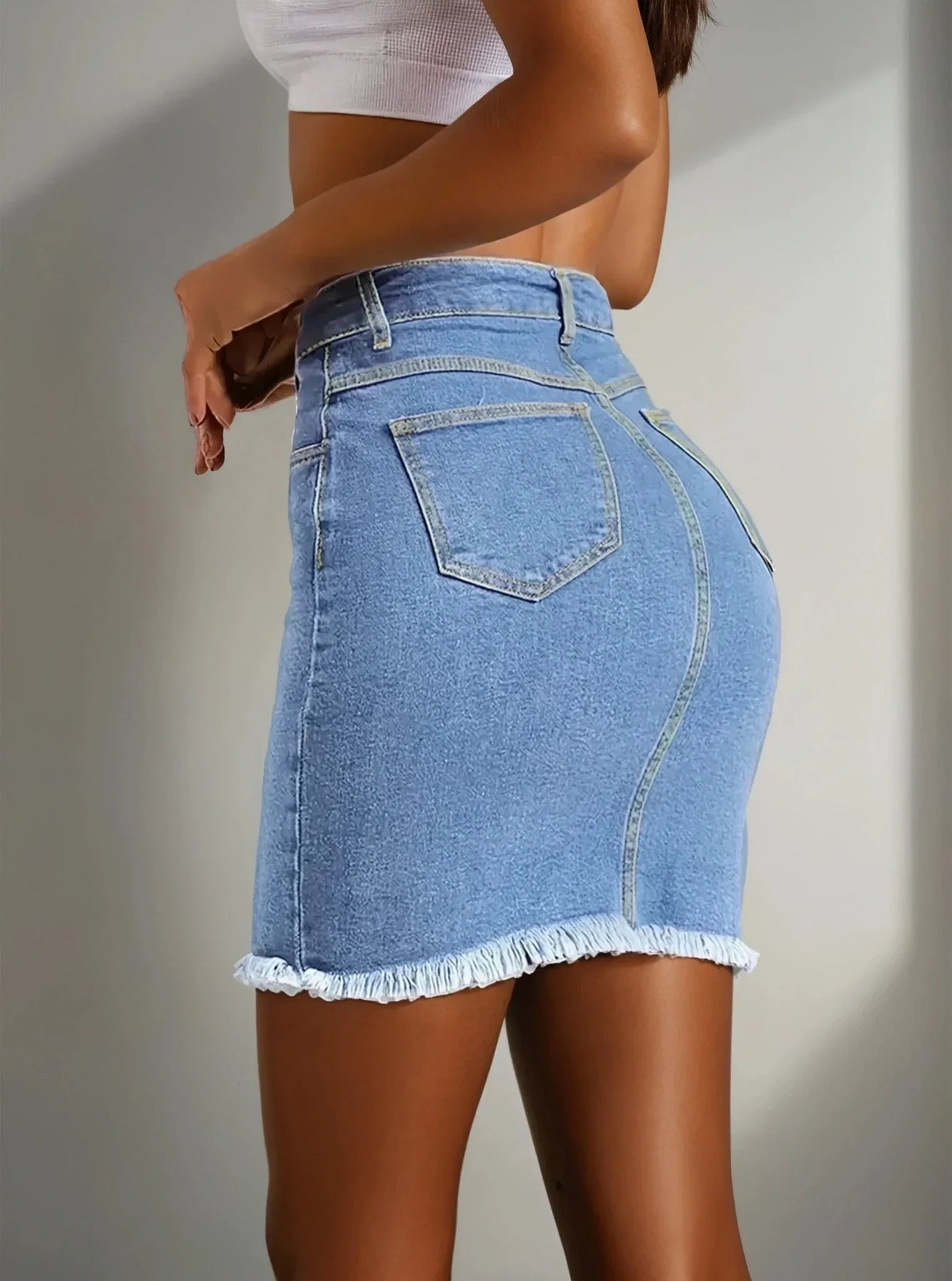 Femme portant une jupe en jean courte tendance, taille haute, finition effilochée, 974 Réunion