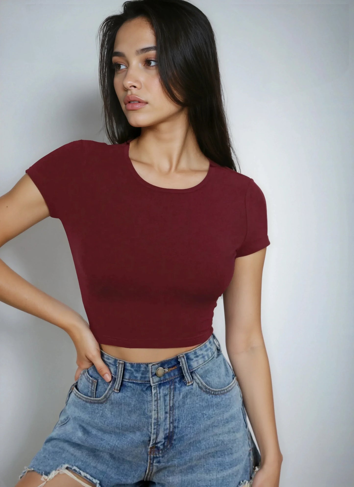 Jeune femme portant un crop top bordeaux et un short en jean tendance, 974 Réunion.