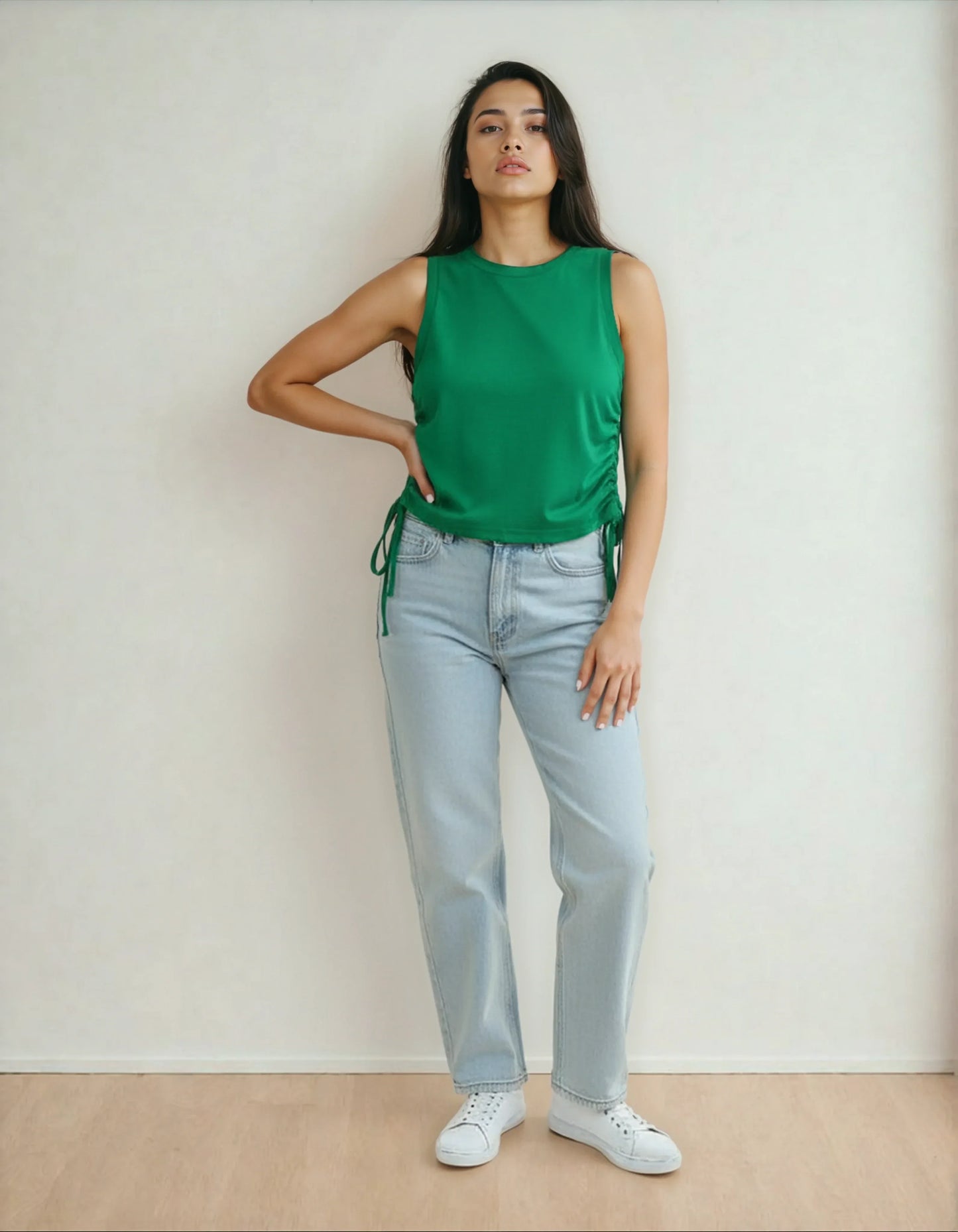 Femme debout en jean clair, débardeur vert et baskets blanches, mode 974 La Réunion