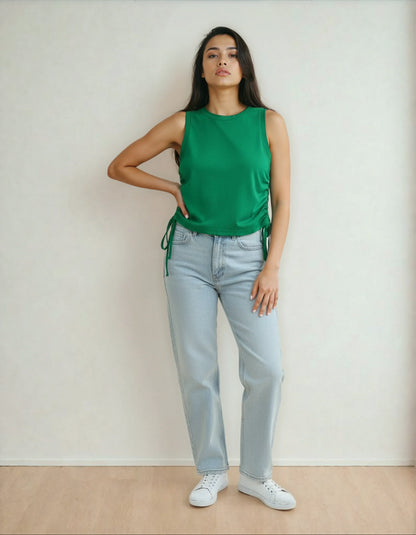 Femme en débardeur vert et jean clair, mode tendance 974 Réunion, pose sur parquet