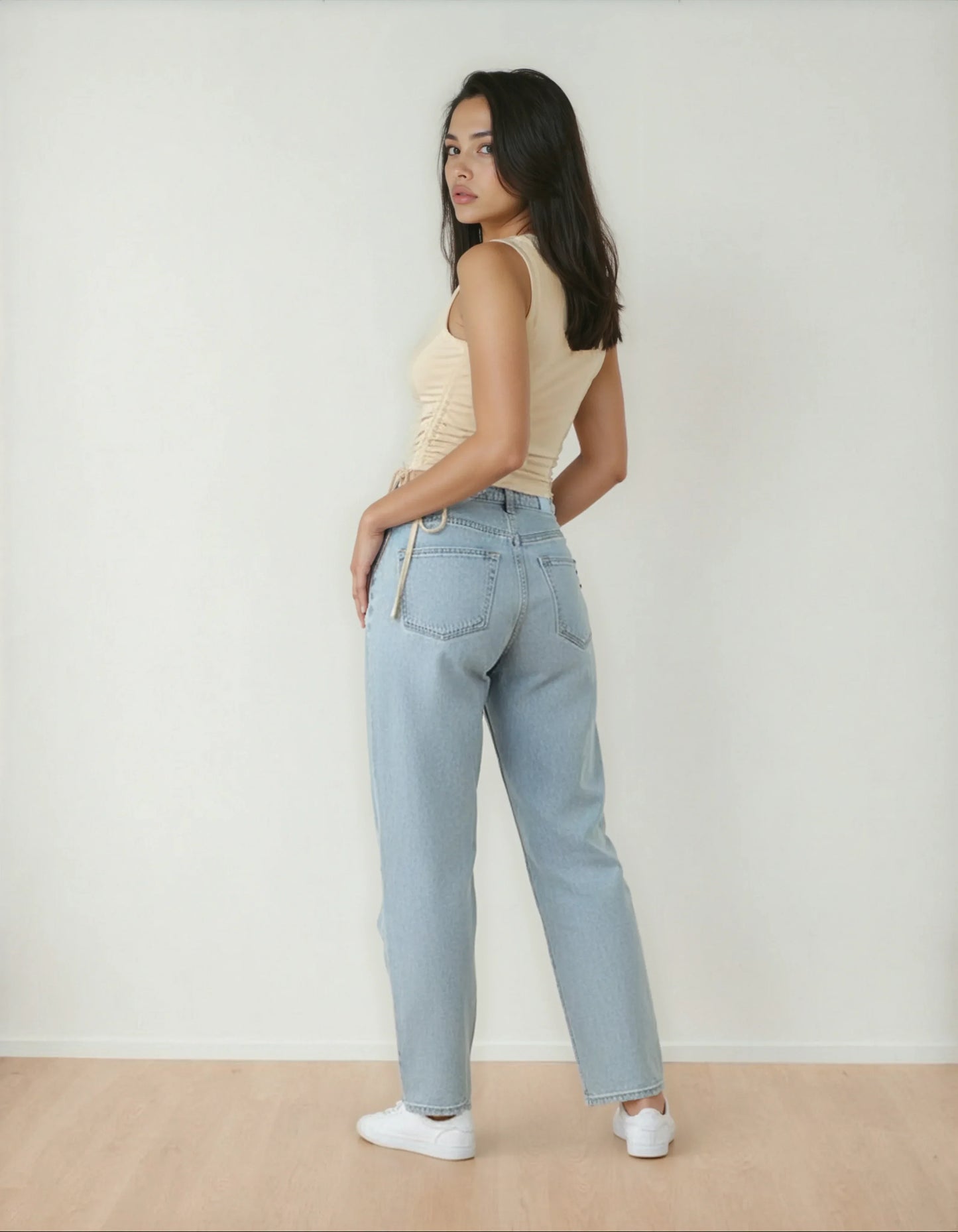 Femme portant un jean clair taille haute et débardeur beige, style tendance 974 Réunion