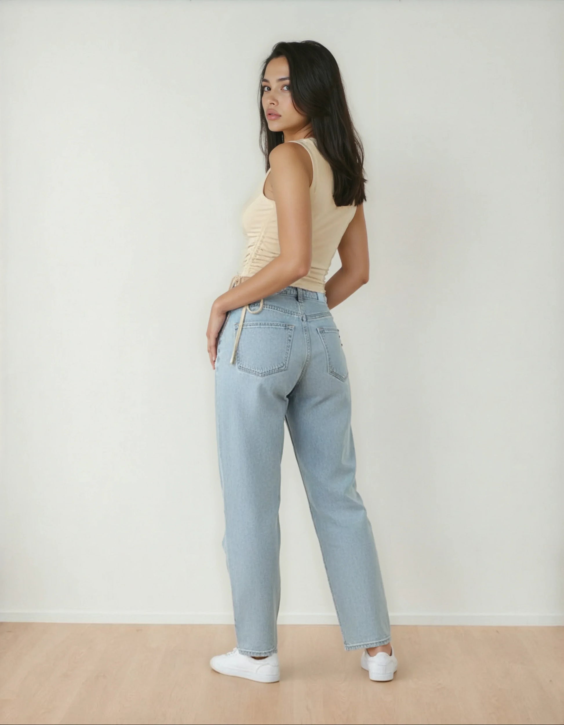 Femme portant un jean clair taille haute et débardeur beige, style tendance 974 Réunion